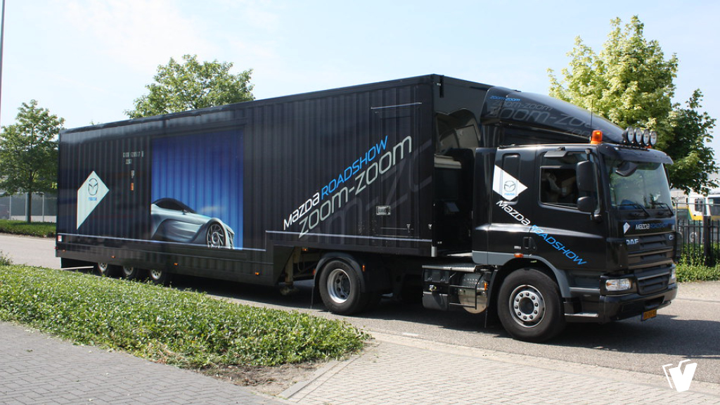 Carwrap trekker van wit naar glans zwart en volledige full-colour wrap van oplegger.